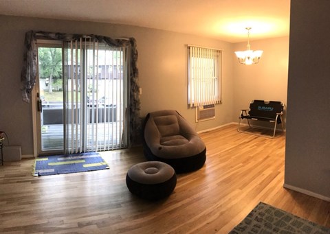 A living room with a grey chair and ottoman, a blue rug, and a chandelier.