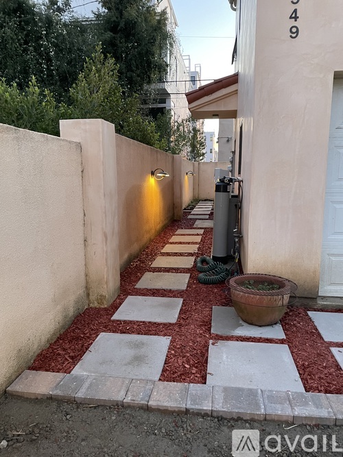 A red and white tiled walkway leads to a white door.