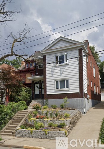 A white house with a grey roof and a small garden in front.