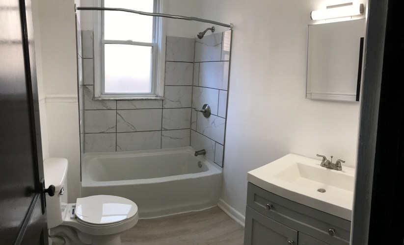 A white toilet sits next to a bathtub in a bathroom.