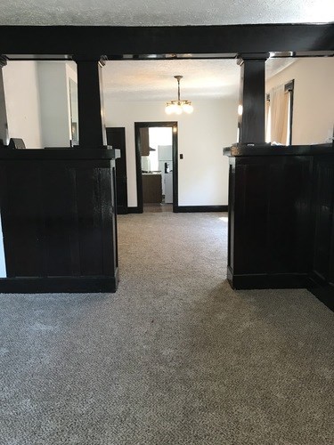 A hallway with a carpeted floor and a chandelier hanging from the ceiling.