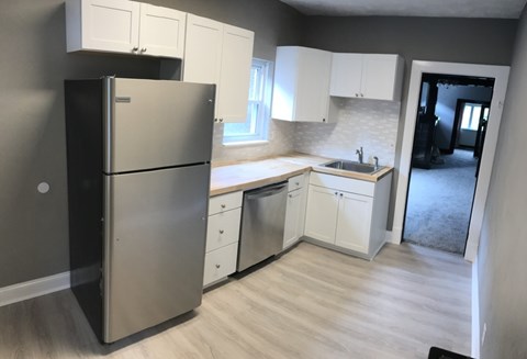 A kitchen with a black refrigerator and white cabinets.