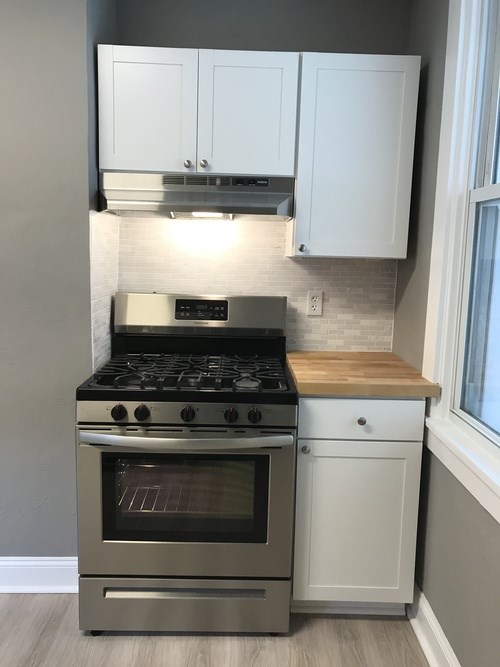 A modern kitchen with a stainless steel oven and white cabinets.