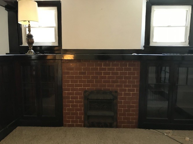 A room with a fireplace and a lamp on a table.