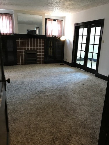 A room with a carpeted floor and a fireplace.