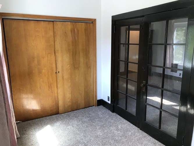 A room with a wooden door and a black door with glass panes.