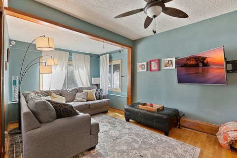 A living room with a grey couch and a ceiling fan.