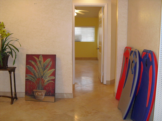 A room with a yellow wall and a painting of a plant on the floor.
