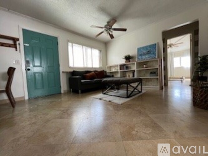 A living room with a couch, a chair, and a ceiling fan.