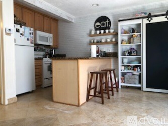 A kitchen with a white refrigerator, wooden island, and a black fridge freezer.