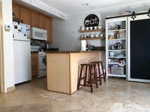 A kitchen with a white refrigerator, wooden island, and a black fridge freezer.