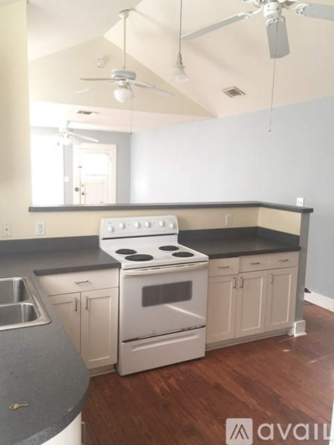A kitchen with a stove top oven and a fan ceiling light.