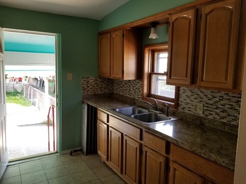 A kitchen with green walls and wooden cabinets.