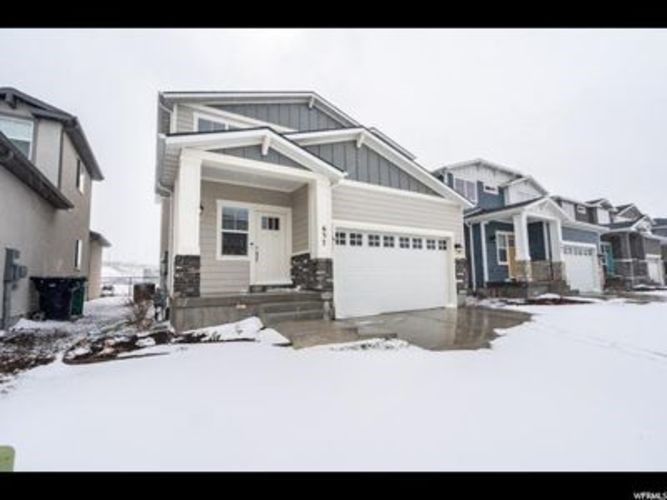 A house with a white garage door is surrounded by snow.