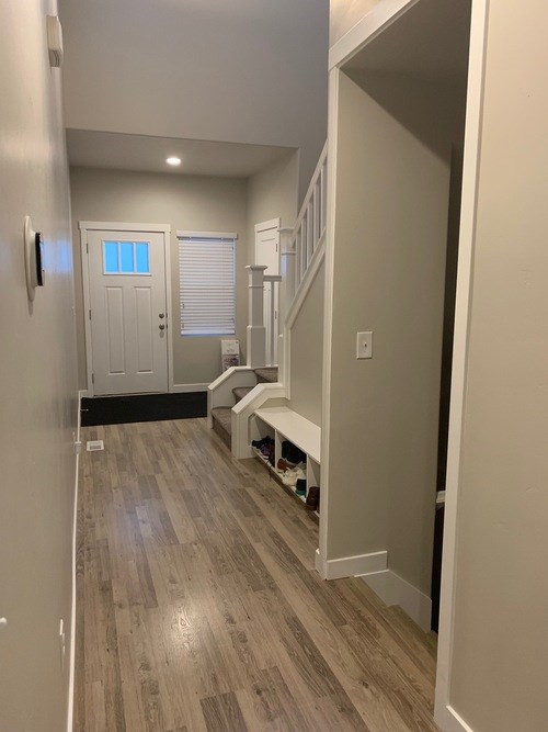 A hallway with a bench and a door.