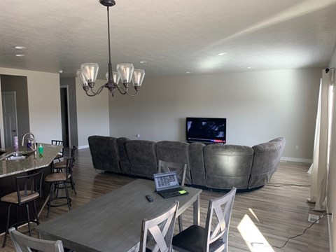 A modern living room with a grey couch and a wooden dining table.