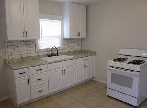 A white kitchen with a stove and sink.