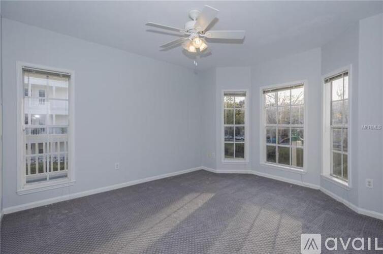 A spacious room with a ceiling fan and large windows.