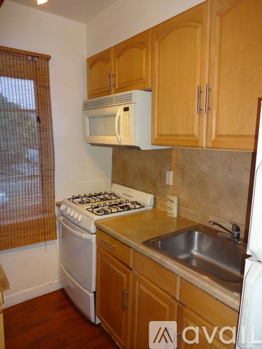 A kitchen with wooden cabinets and a white microwave above the stove.