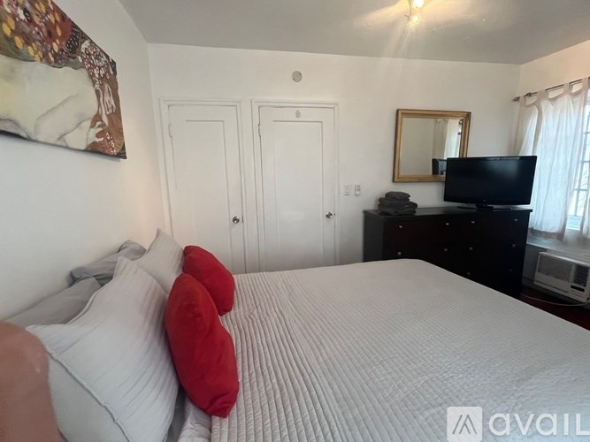 A bedroom with a large bed, a television, and a mirror.