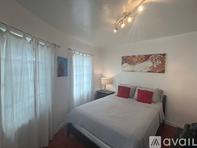 A bedroom with a bed, a lamp, and a painting on the wall.