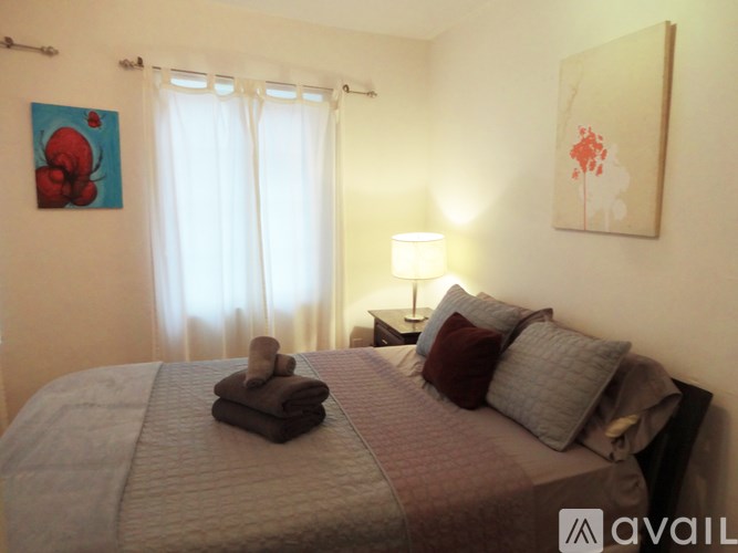 A bedroom with a large bed and a painting on the wall.