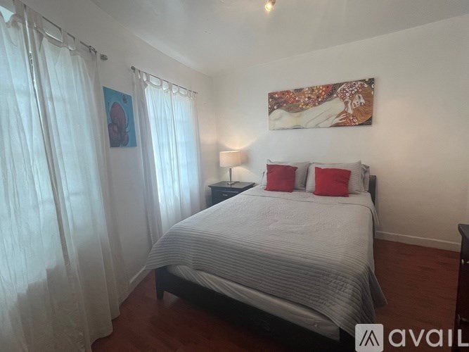 A bedroom with a bed, nightstand, and a painting on the wall.