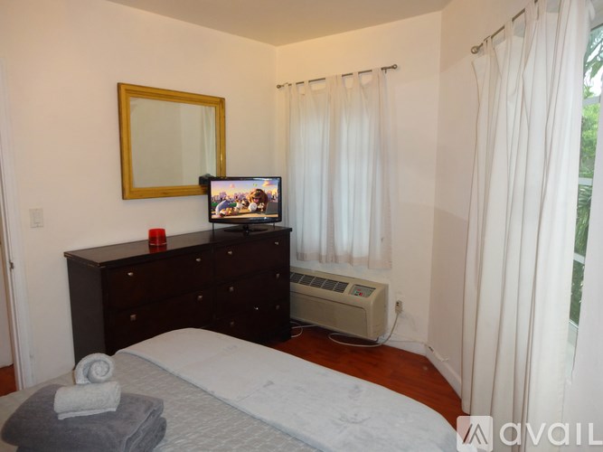A bedroom with a bed, dresser, mirror, and a television.