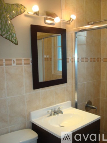 A bathroom with a toilet, sink and mirror.