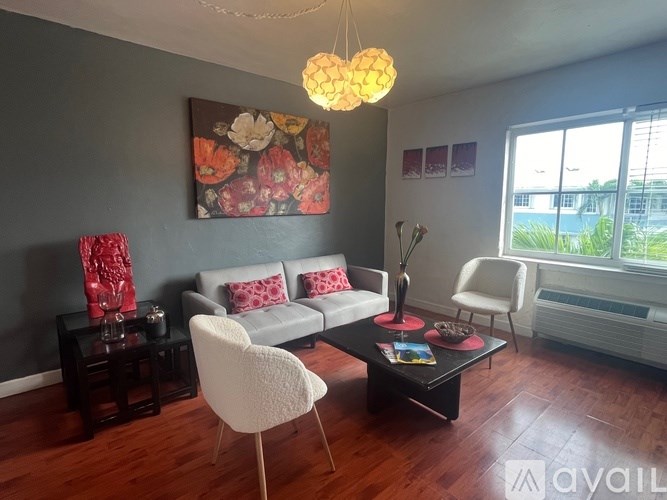A living room with a grey couch, a white chair, a coffee table, and a painting on the wall.
