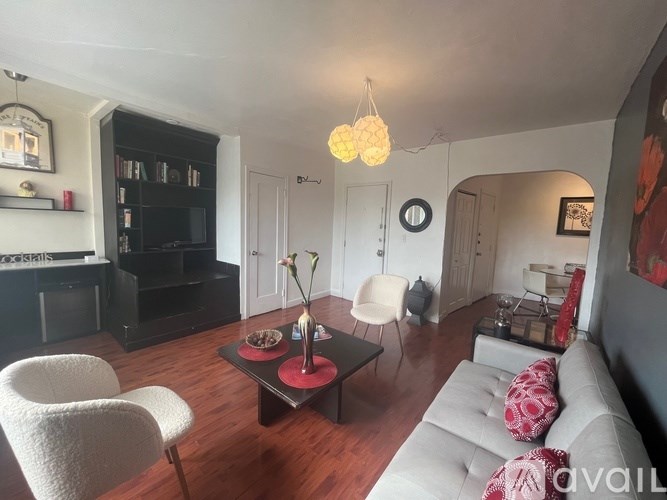 A living room with a white sofa, a black bookshelf, and a white chair.