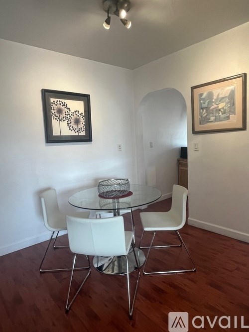 A dining room with a glass table and white chairs.