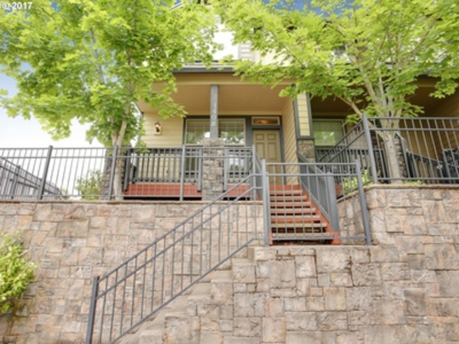 A house with a stone wall and a metal staircase.