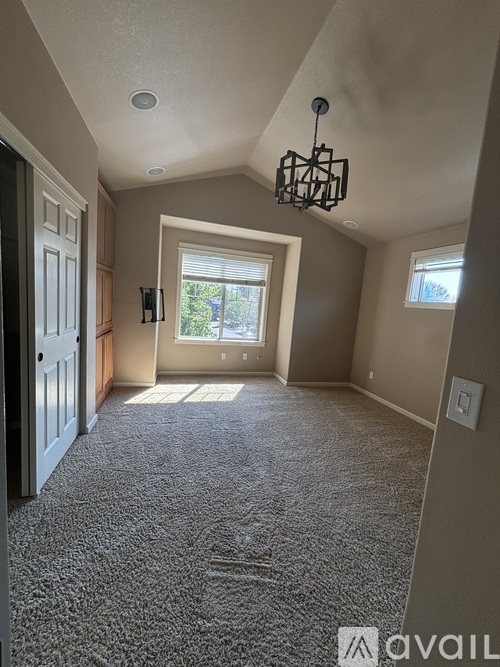 A spacious room with a carpeted floor and a chandelier hanging from the ceiling.