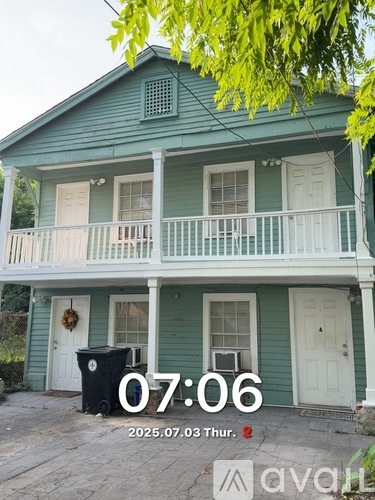 A two-story house with a front porch and a fence.