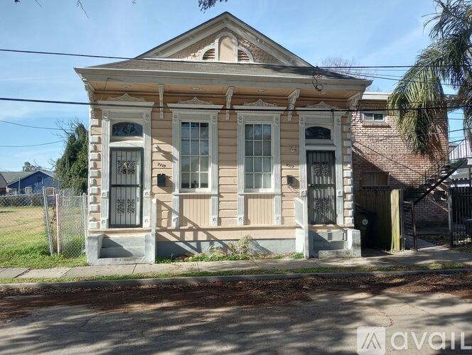 A two-story house with a front porch and a fence.
