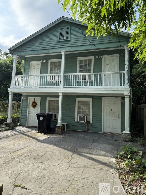 A white house with a porch and a tree in front.
