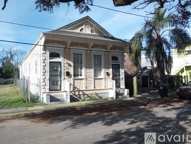 A white house with a porch and a tree in front.