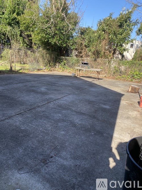 A concrete area with a bench and trees in the background.