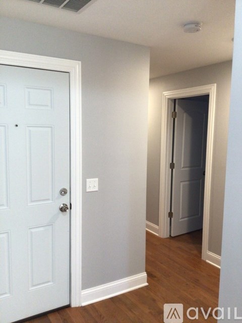 A white door is open to a dark hallway.