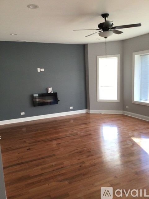 A room with a ceiling fan and wooden flooring.