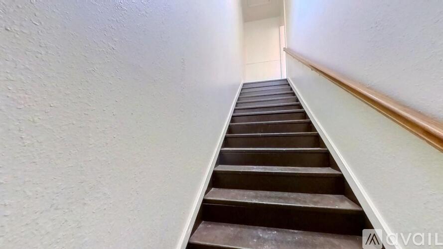 A staircase with a wooden handrail leading upwards.