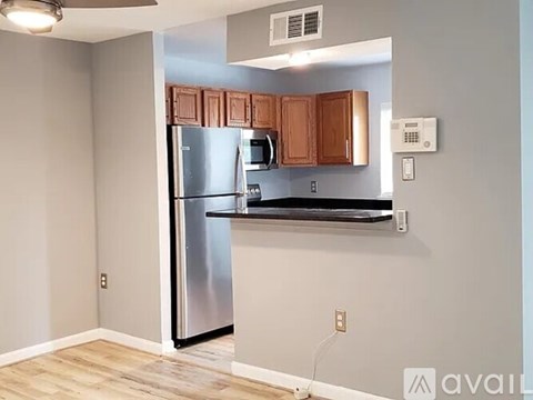A kitchen with a stainless steel refrigerator and wooden cabinets.