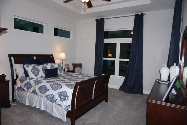 A bedroom with a bed, nightstand, and window with curtains.