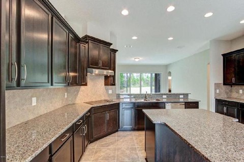 A kitchen with dark wood cabinets and granite countertops.