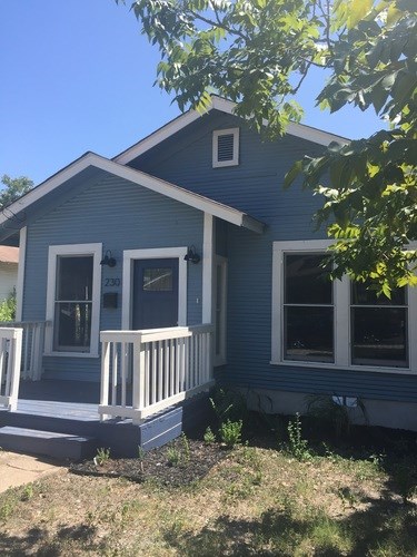 A blue house with a white porch and windows.