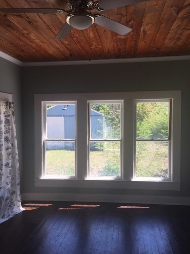 A room with a ceiling fan and three windows.