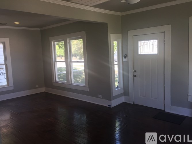 A room with a white door and a window with a view of trees.