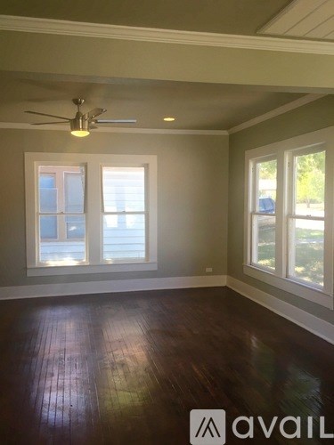 A room with a ceiling fan and two windows.