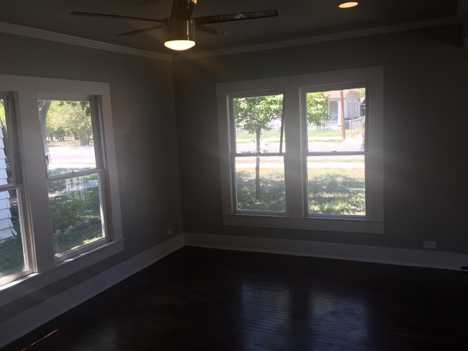 A room with a ceiling fan and two windows.